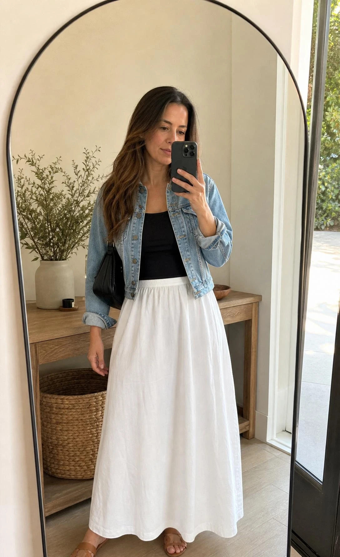 Mirror selfie of a white maxi skirt outfit with a light denim jacket, fitted black bodysuit, and softly draped cotton skirt