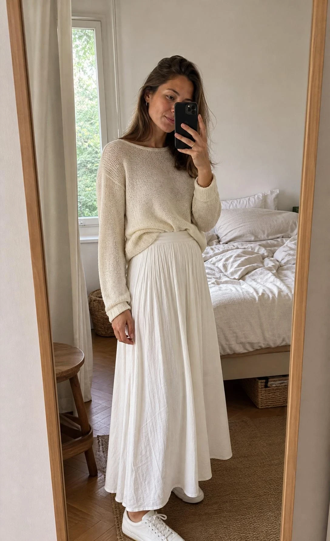 Bedroom mirror selfie of a woman styling a fine-knit sweater, white flowing skirt, and sneakers for white maxi skirt outfit ideas