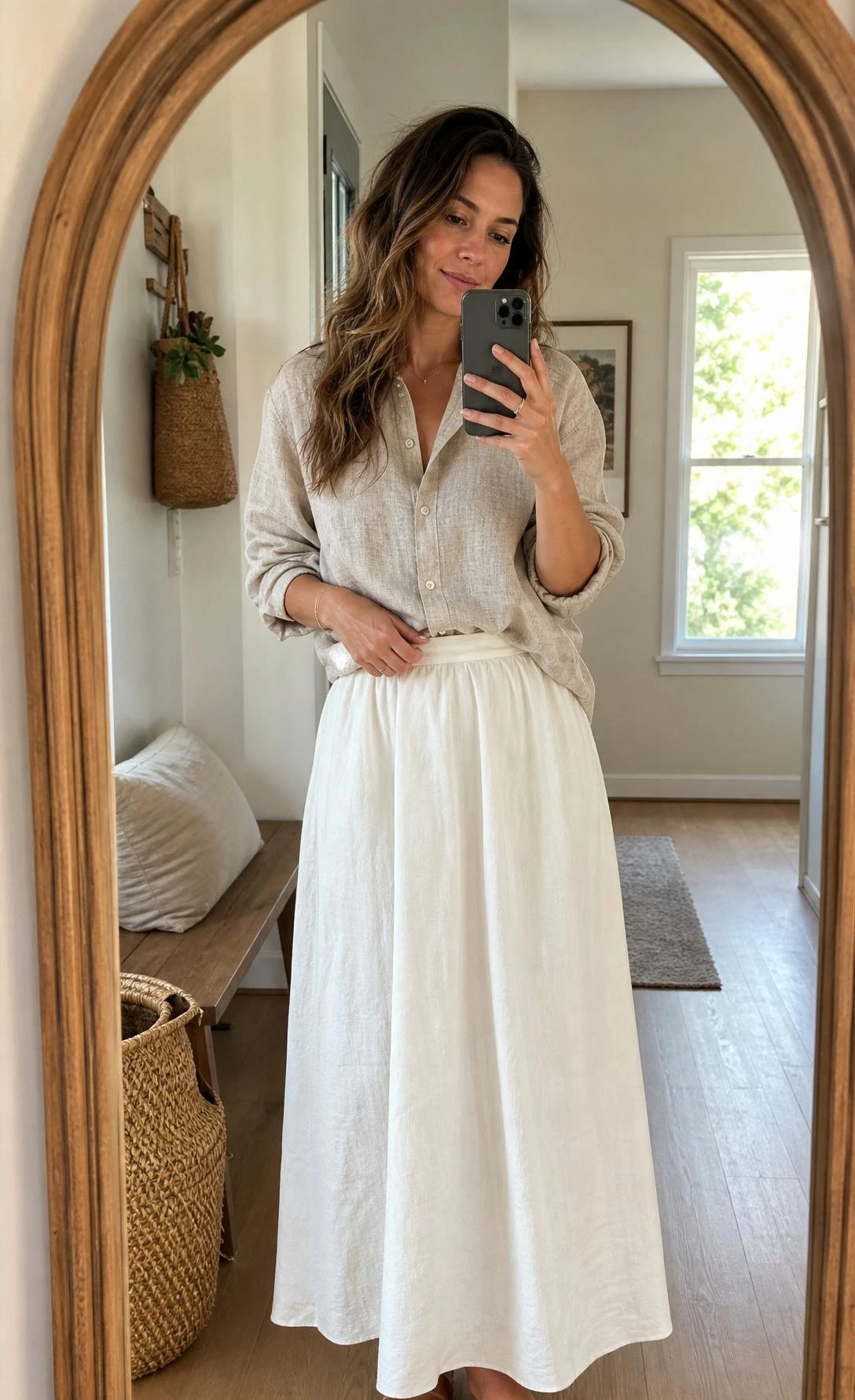 Mirror selfie of a woman styling white maxi skirt outfit ideas with an oatmeal linen button-up and leather slides