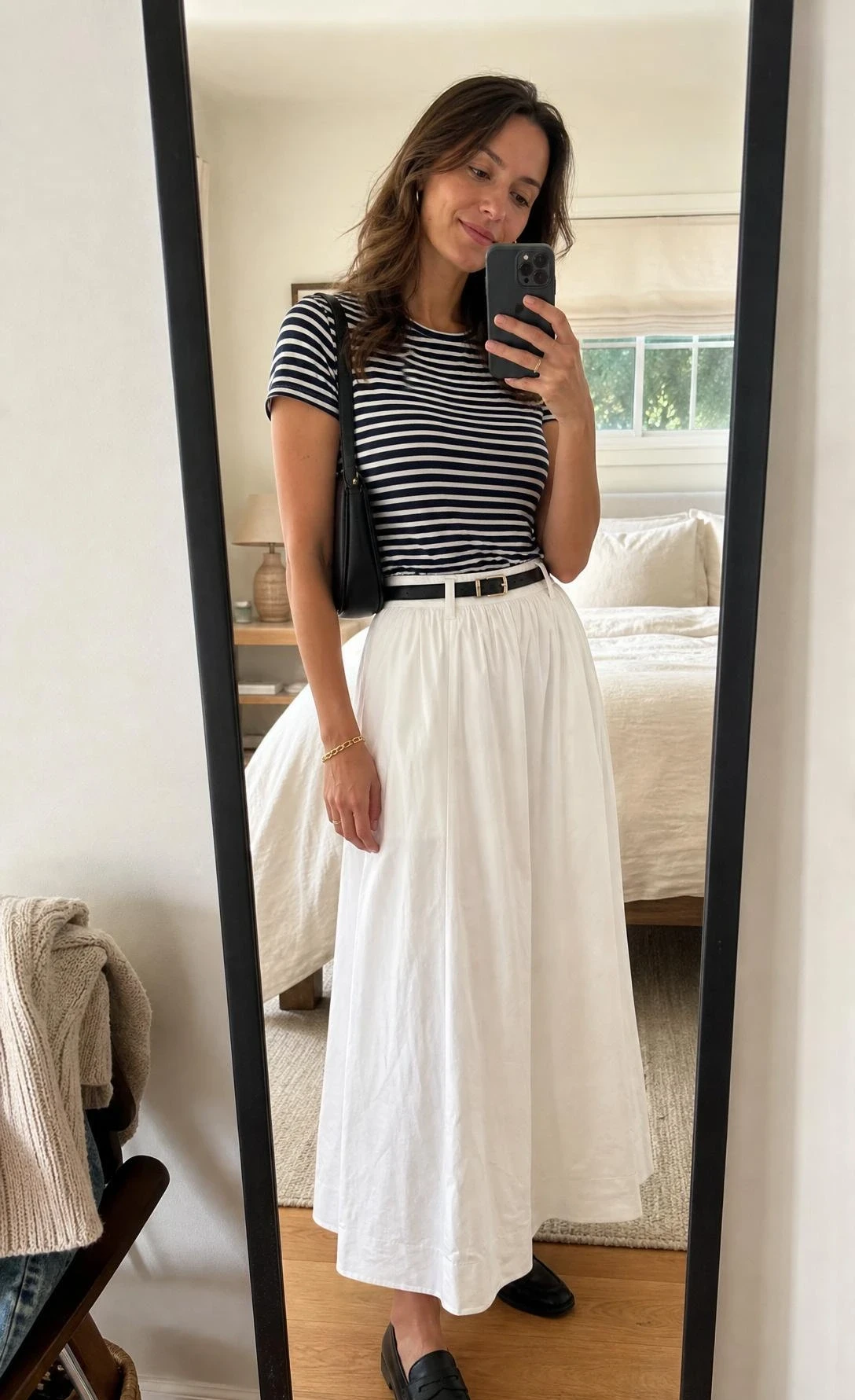 Woman in a striped tee and black loafers poses in a bedroom mirror for white maxi skirt outfit ideas