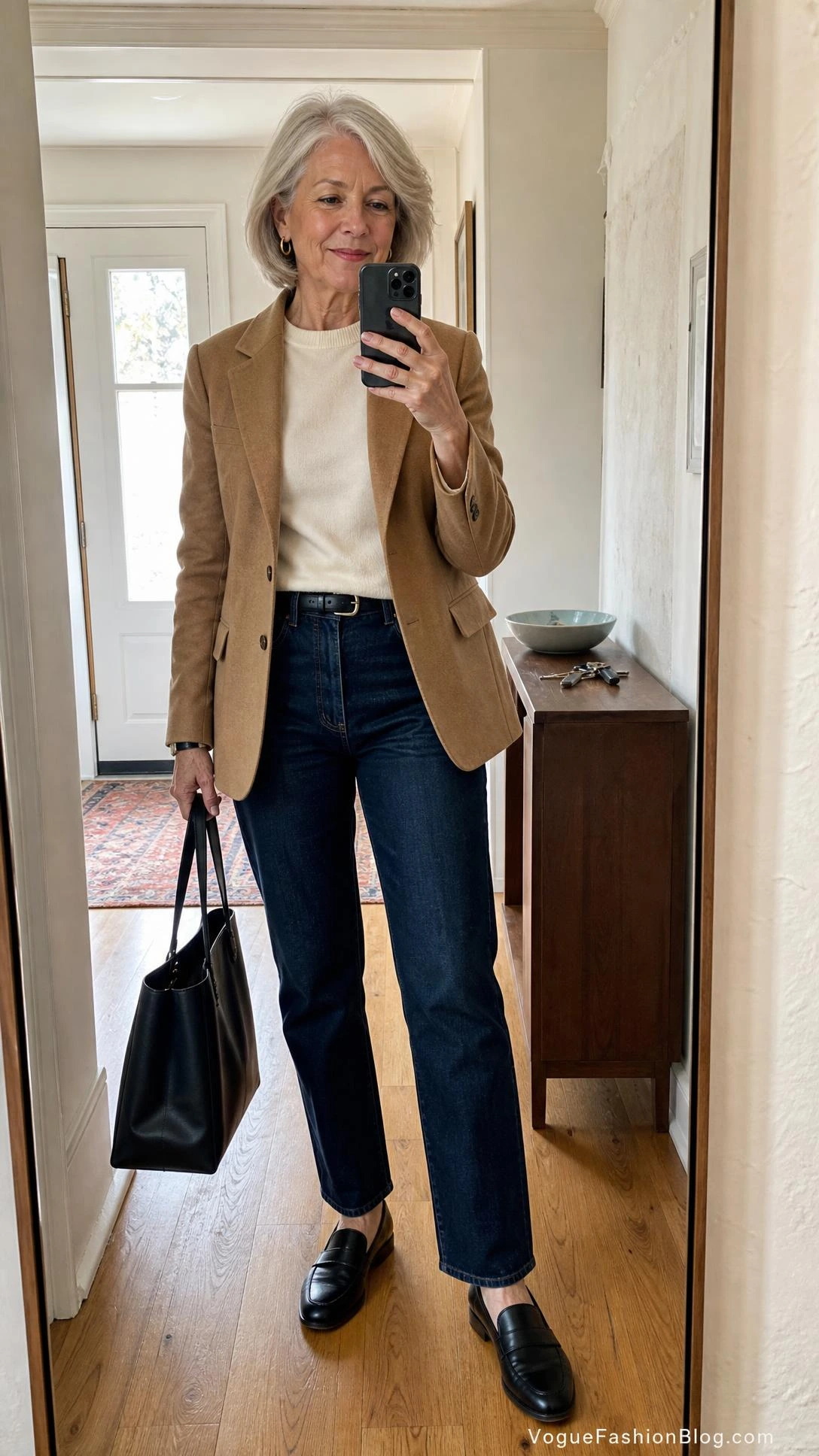 Stylish woman in her early 70s wearing a camel blazer, cream knit, and dark indigo jeans shows how to dress in your 70s with a wardrobe base