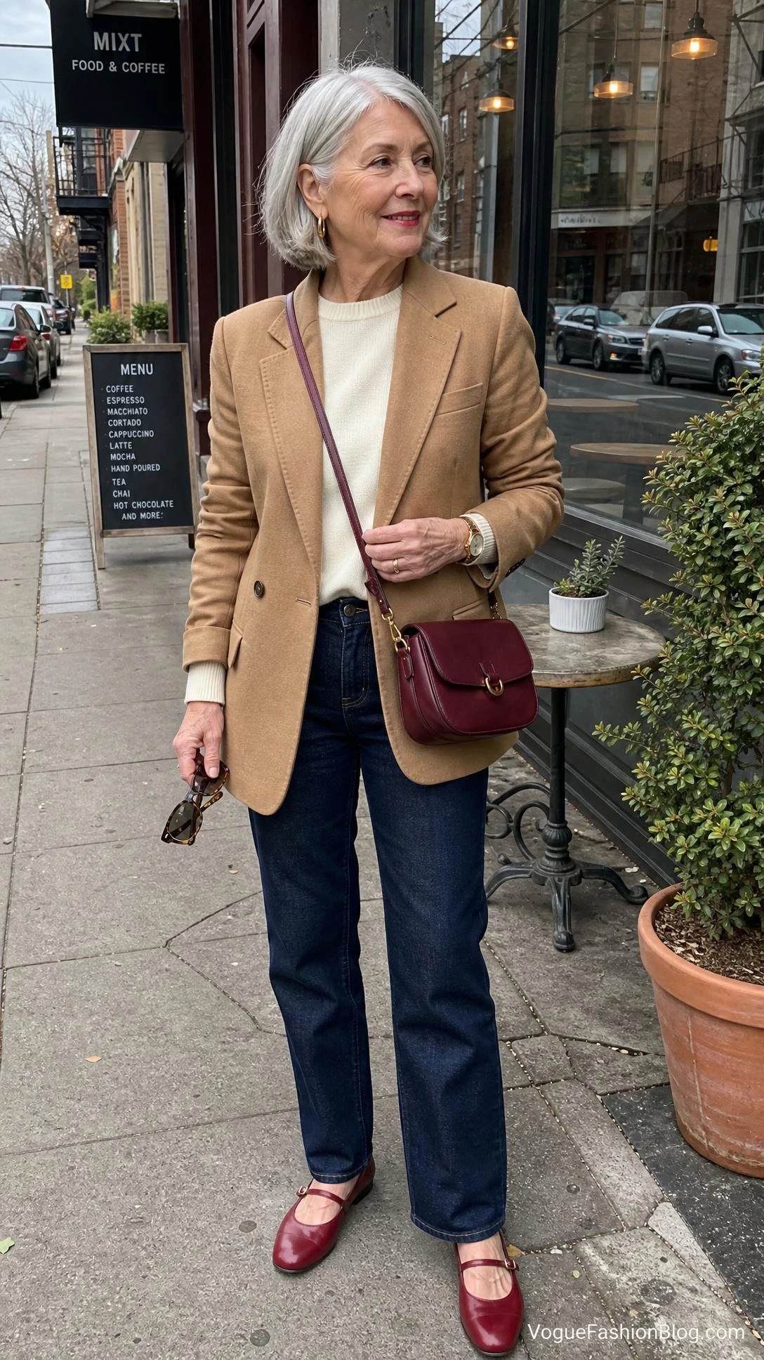 Stylish silver-haired woman outside a neighborhood café shows how to dress in your 70s with one personal trend accent.