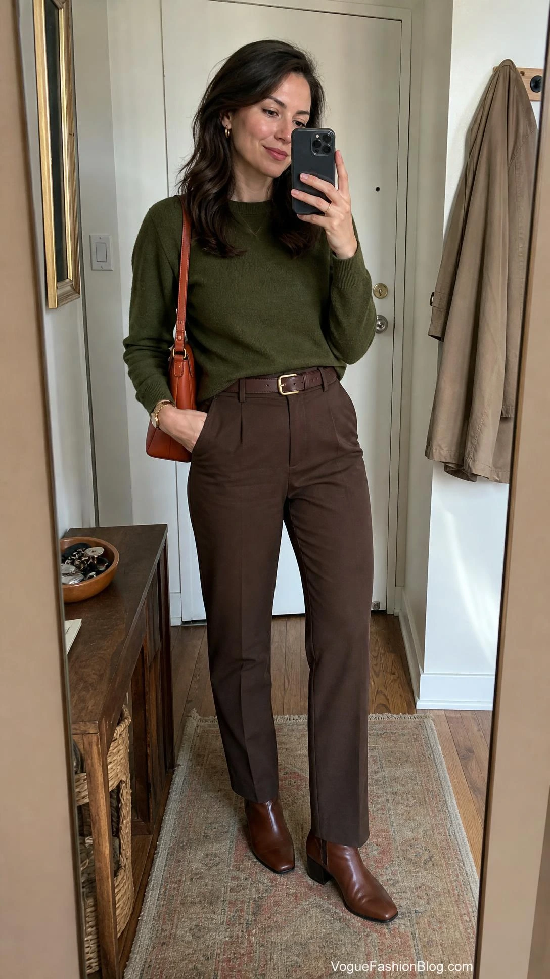 Mirror selfie of a woman styling a persimmon orange outfit with a structured shoulder bag, olive layers, brown pieces, and fall shoes