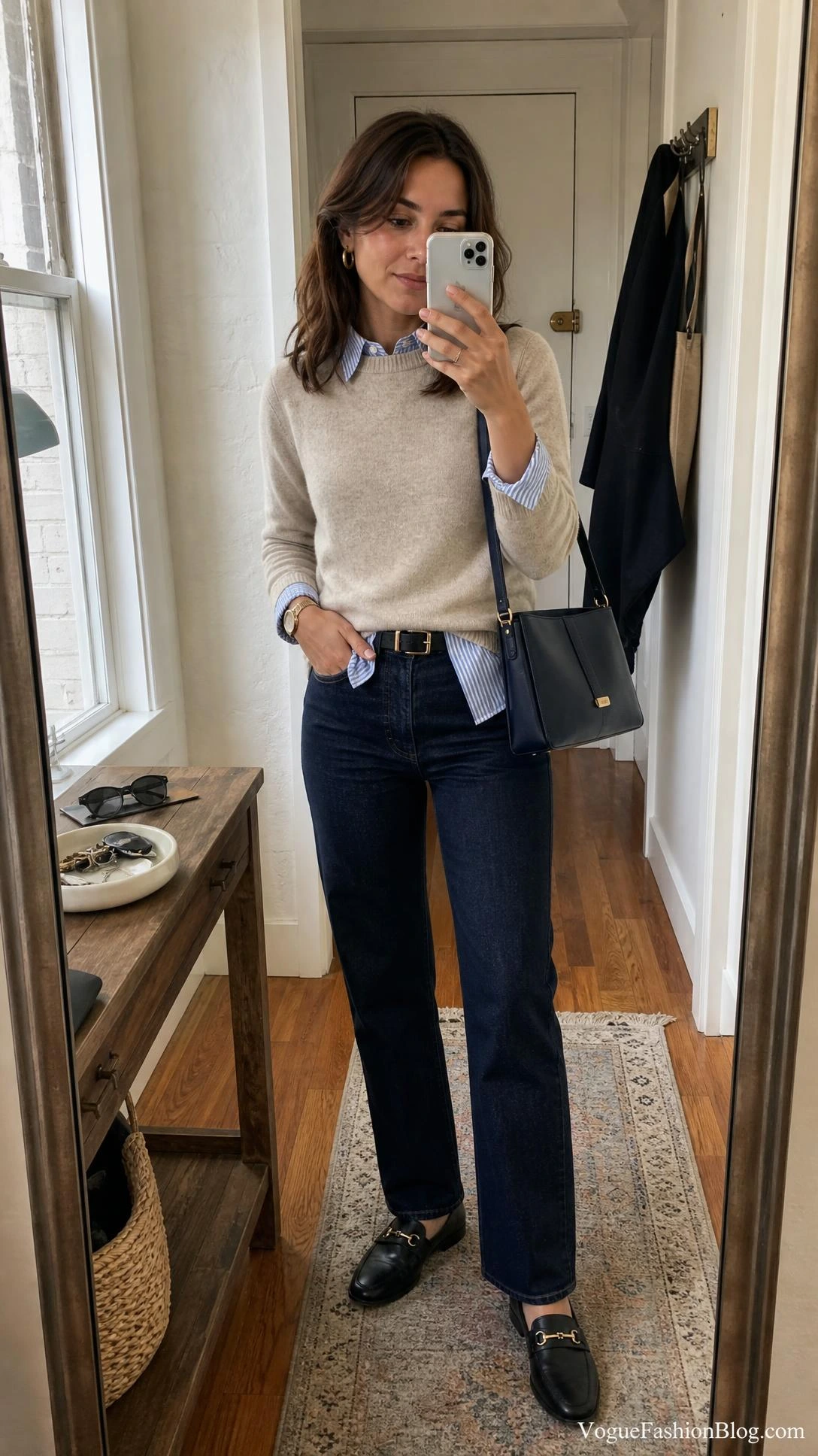 Entryway mirror selfie showing striped shirt outfits styling: blue button-down under an oatmeal sweater for early fall.