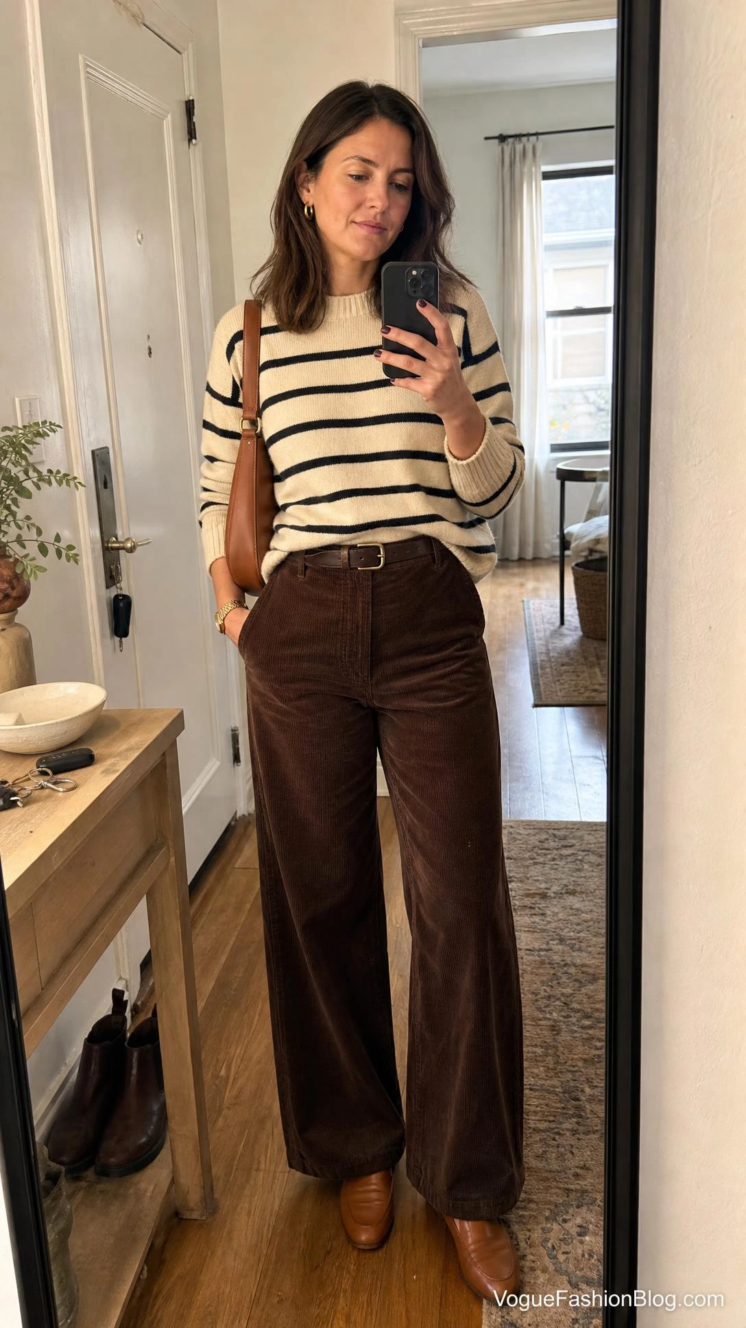Woman taking a mirror selfie in a striped sweater and corduroy pants, a fresh take on fall outfit ideas.