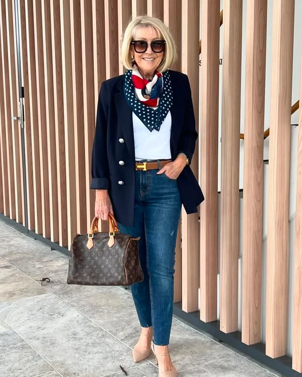Woman wearing a navy blazer, white wide-leg trousers, red-patterned silk neck scarf, and nude pumps.