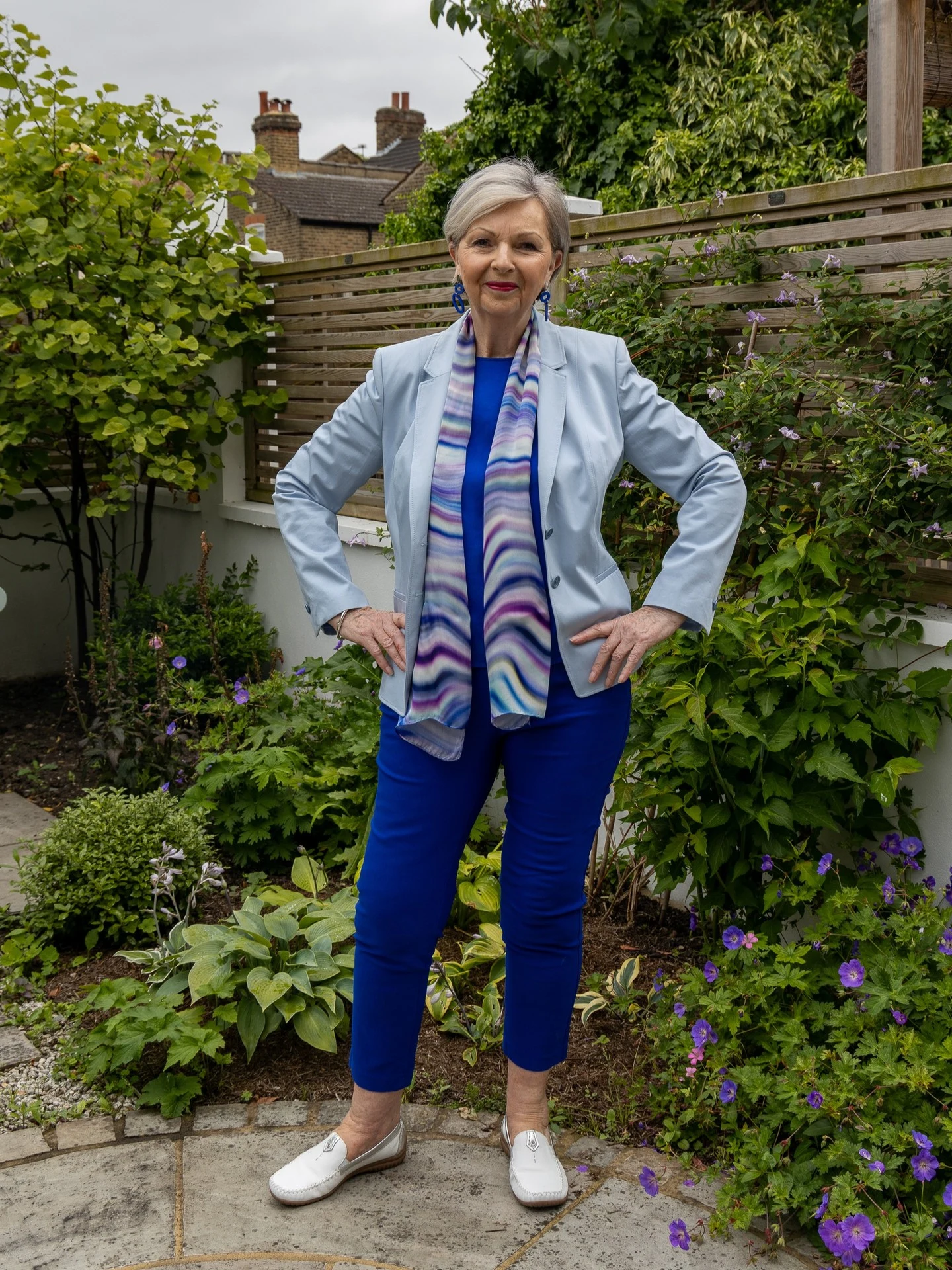 Light blue blazer, blue crewneck, white wide-leg trousers, and colorful striped silk neck scarf styled together.