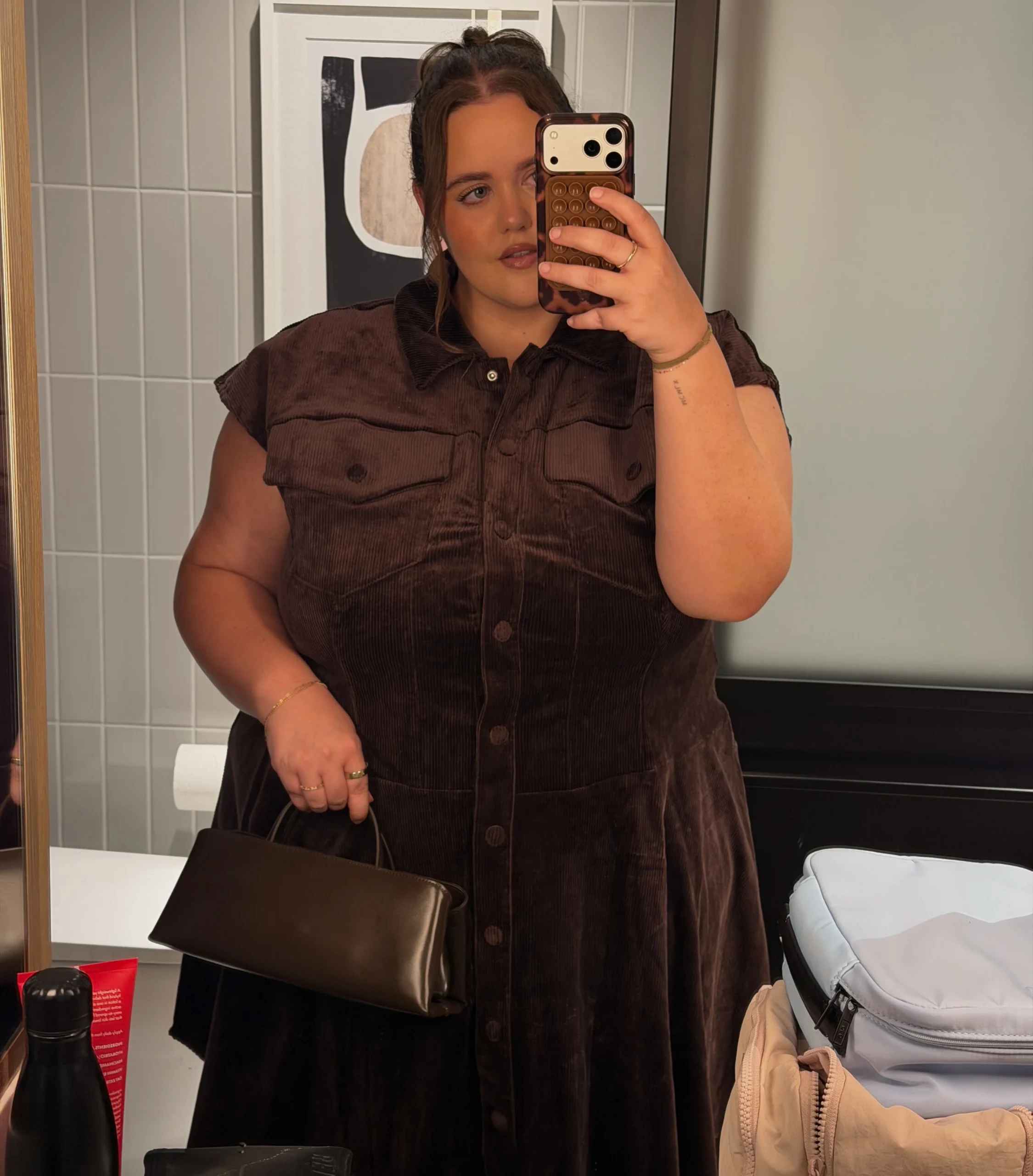 Creator Taylor Tharp in brown sleeveless collared button front corduroy midi dress with chest pockets and small brown structured bag - mirror selfie fall 90s corduroy dress.