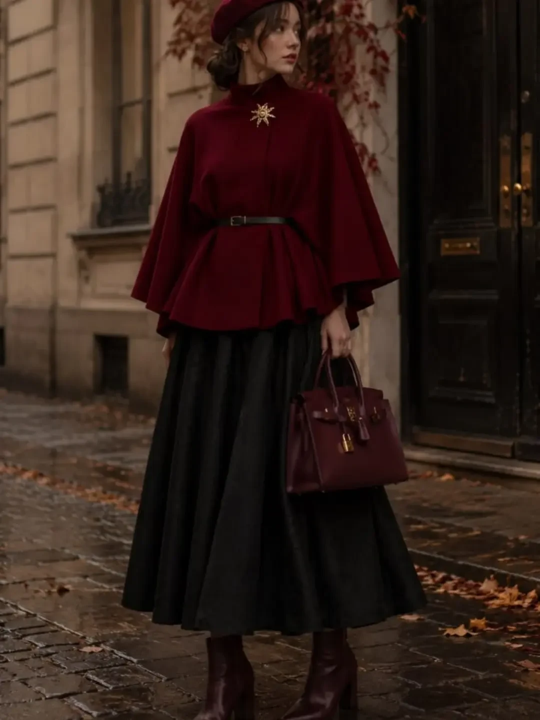 Full burgundy outfit with beret, belted cape top, black midi skirt, heeled boots, and gold-hardware bag.