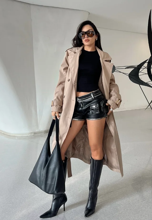 Beige Trench Coat + Black Cropped Top + Black Leather Shorts + Black Knee-High Stiletto Boots
