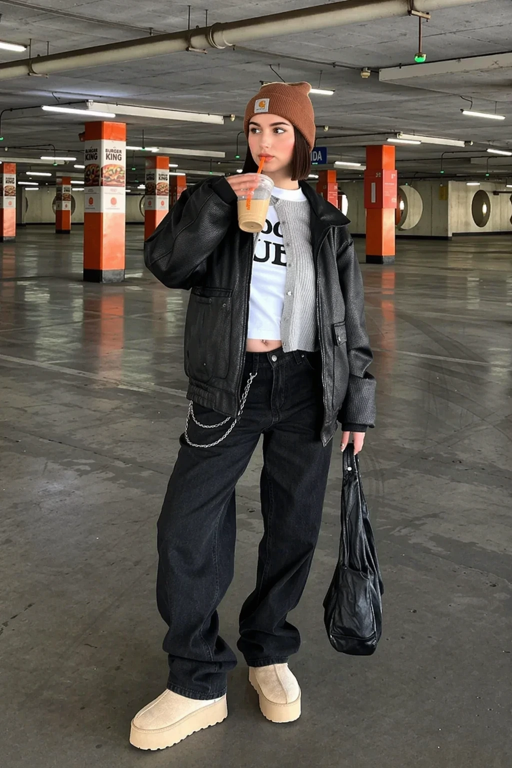 Black Oversized Leather Jacket + White Graphic Crop T-Shirt + Black Wide-Leg Jeans + Beige Platform Slip-On Shoes + Brown Knit Beanie