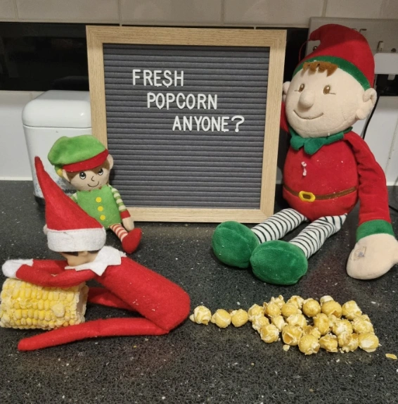 Charming Red and Green Elf Scene with Playful Popcorn Setup