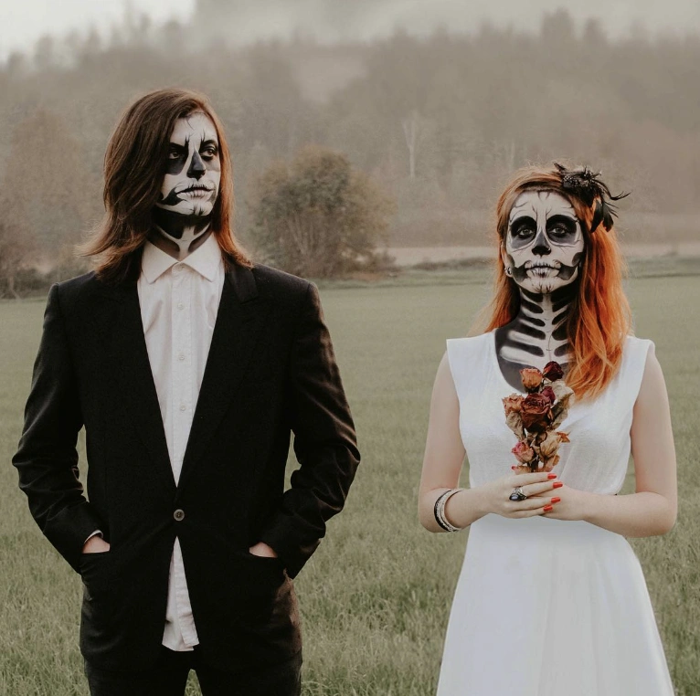 A black suit and a white dress paired with skeleton face paint