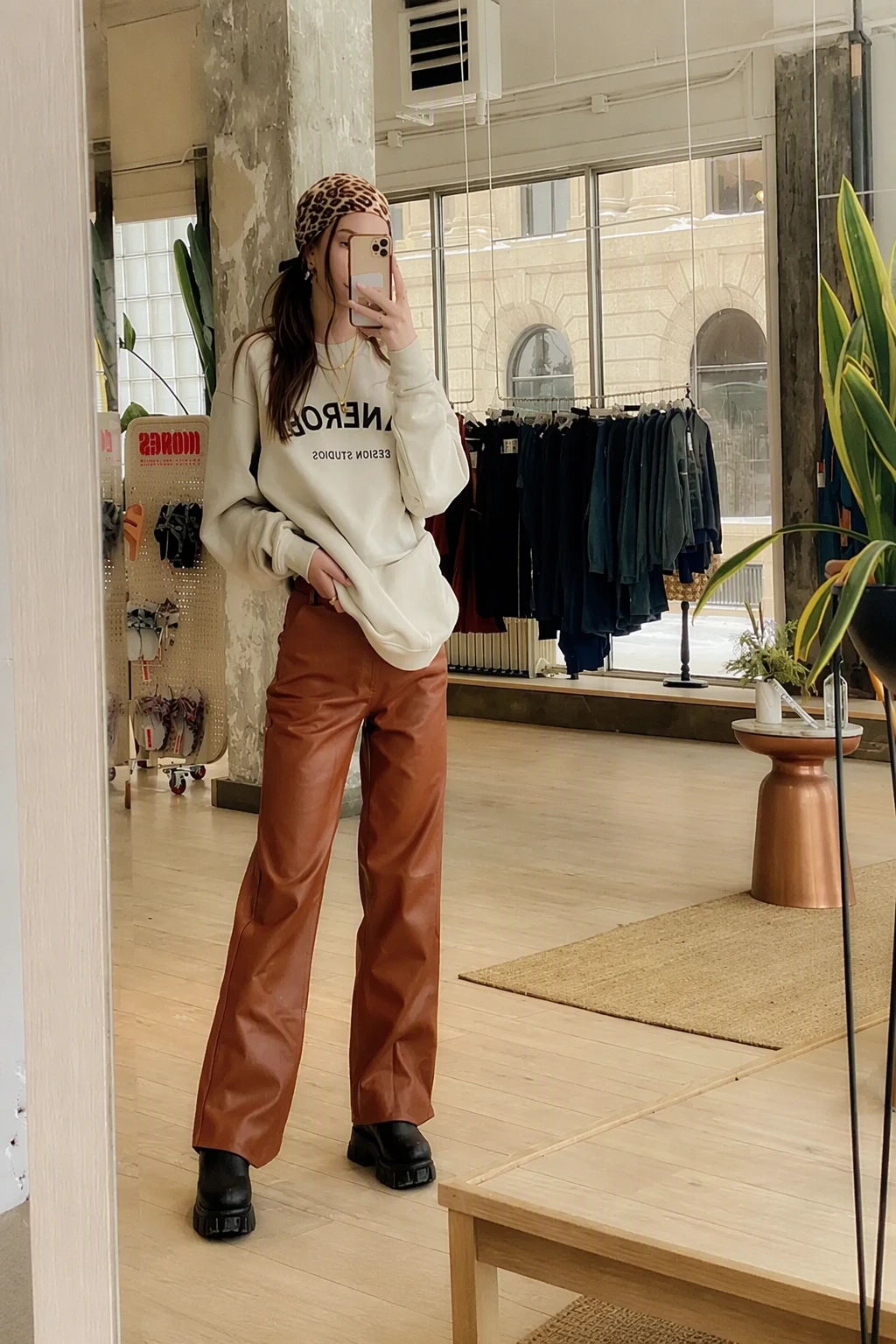Beige Oversized Graphic Sweatshirt + Brown Leather Straight-Leg Pants + Black Platform Ankle Boots + Leopard Print Headscarf