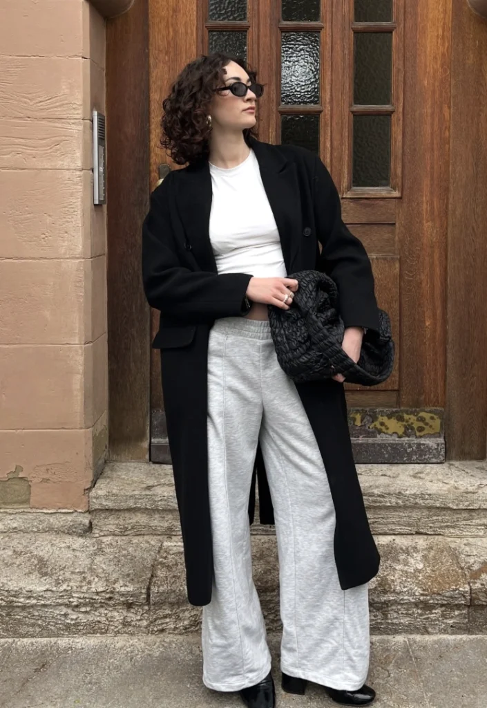 Black Long Coat + White Crop Top + Light Gray Wide-Leg Sweatpants + Black Quilted Ankle Boots