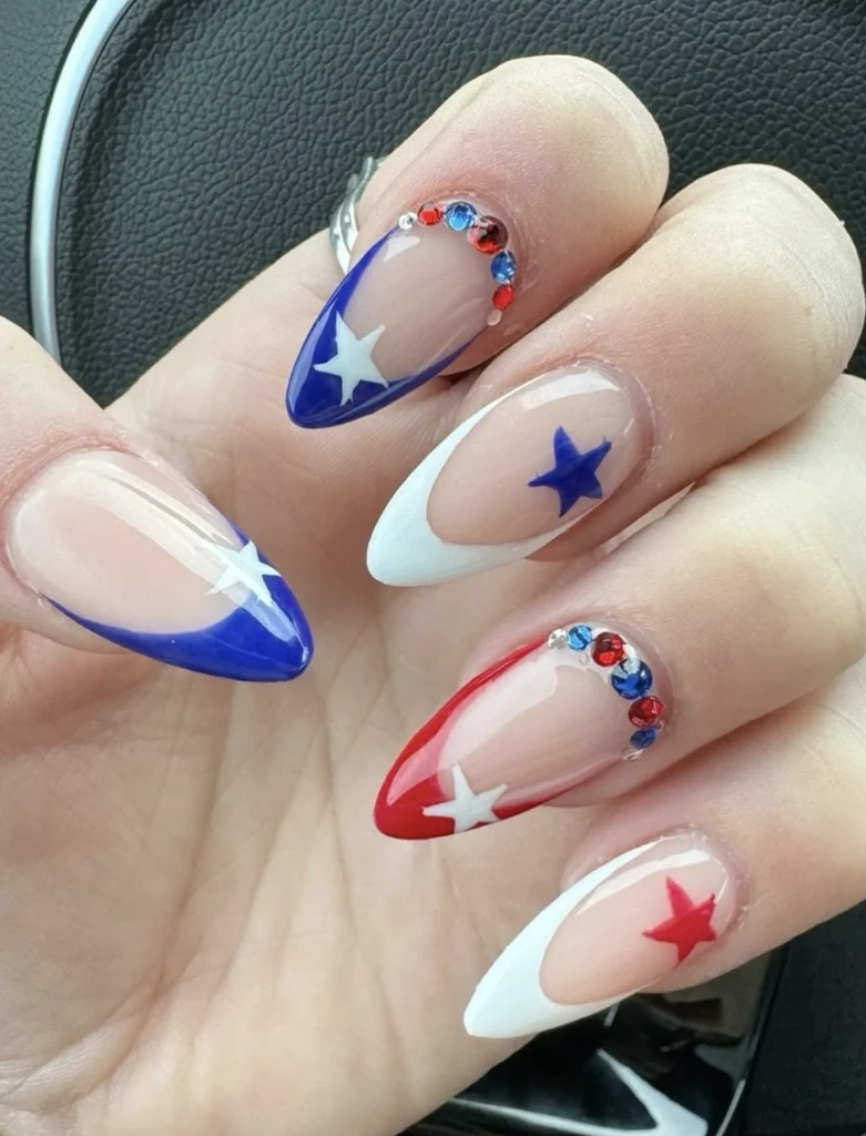 Bold Red, White, and Blue Stiletto Nails with Star Accents and Sparkling Rhinestones