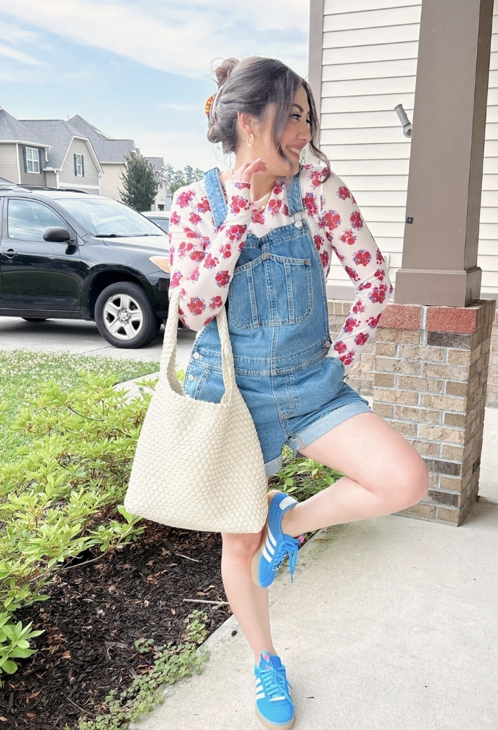 Denim Overall Shorts + Floral Long Sleeve Top + White Woven Handbag + Blue Athletic Sneakers