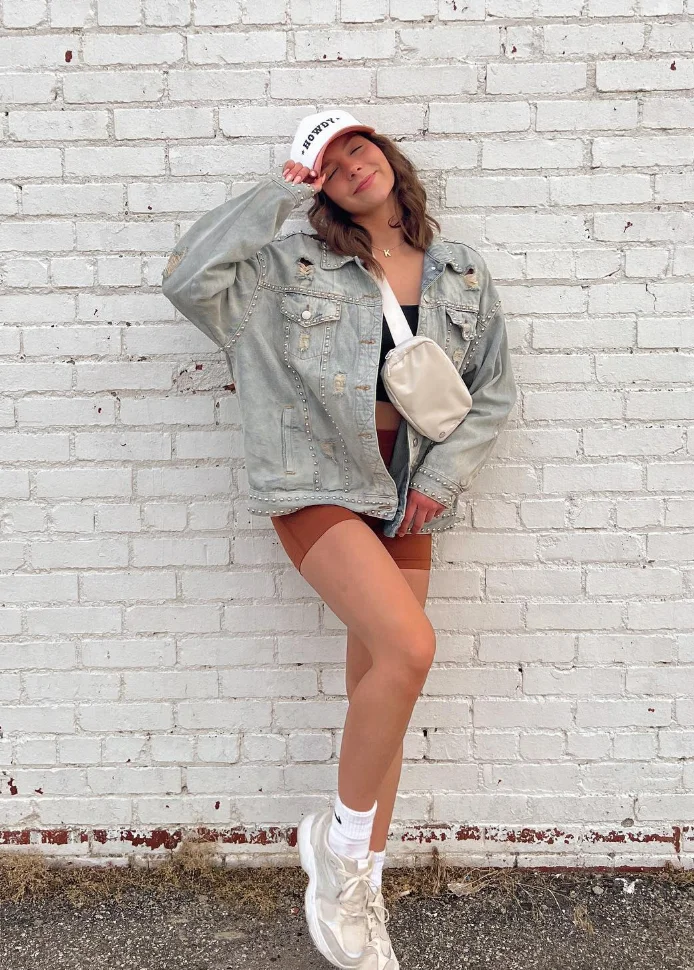 Distressed Denim Jacket + Rust Bike Shorts + White Sneakers