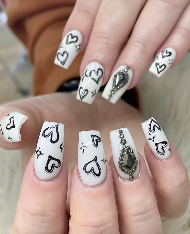 Graphic Black Hearts on Milk-White Nails with Jewel Accent