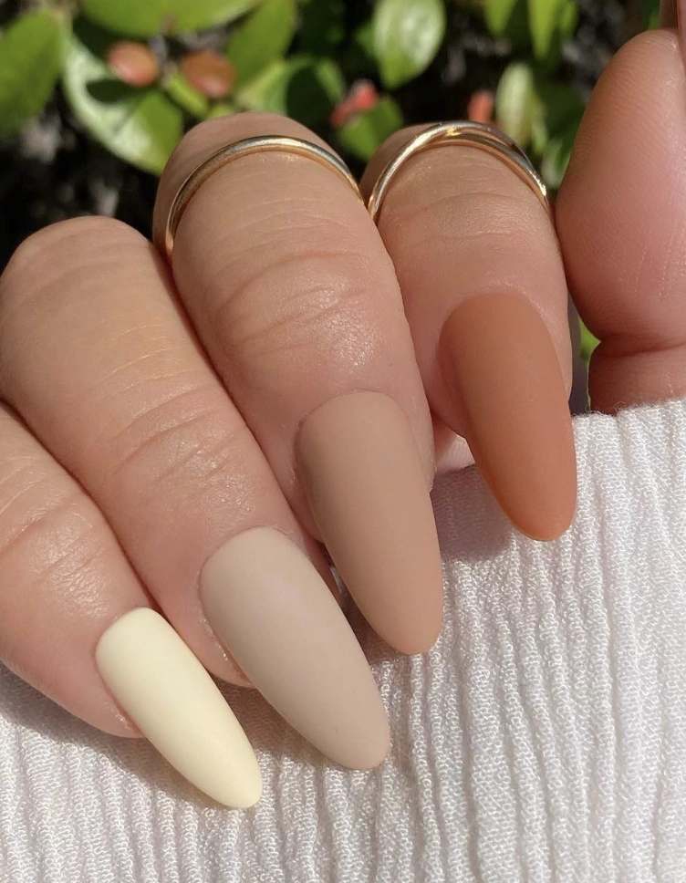 Medium-length nails in soft beige, muted yellow, and warm brown matte finishes