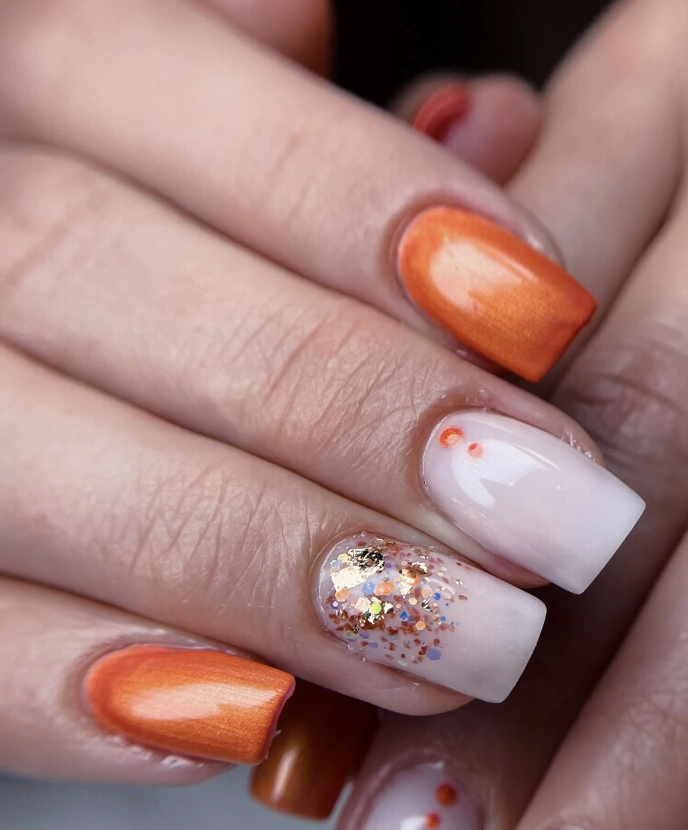 Milky White French Nails with Orange Ombre Tips and Glitter Accents