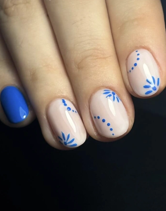 Minimalist Nude Nails with Royal Blue Floral Accents and a Solid Accent Nail