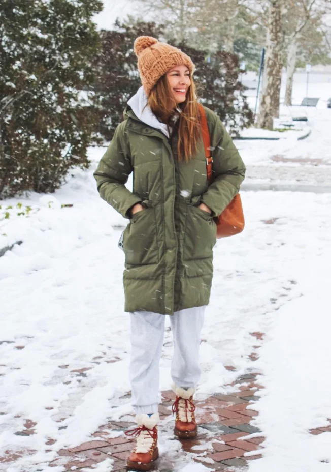 Olive Green Puffer Coat + White Hooded Sweatshirt + Light Gray Joggers + Brown Lace-Up Winter Boots + Tan Knit Beanie