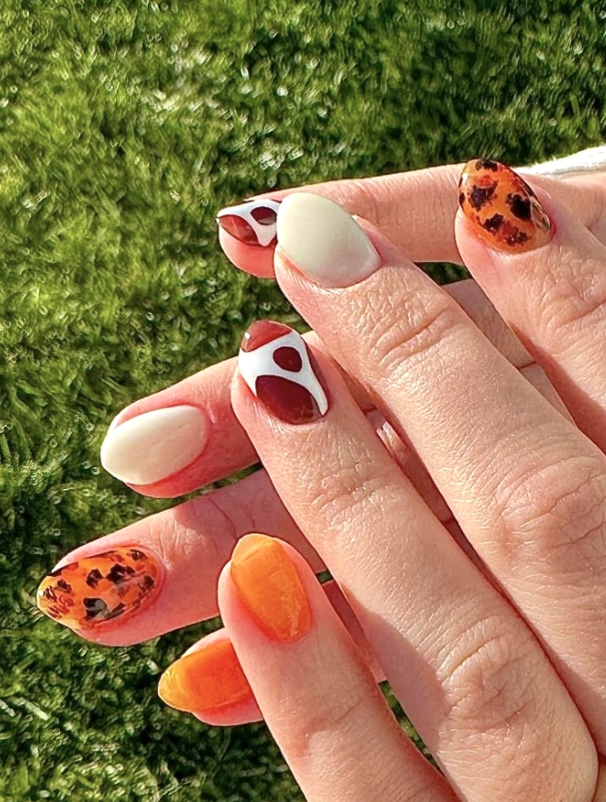 Orange and Burgundy Nails with Whimsical Patterns and Glossy Finish