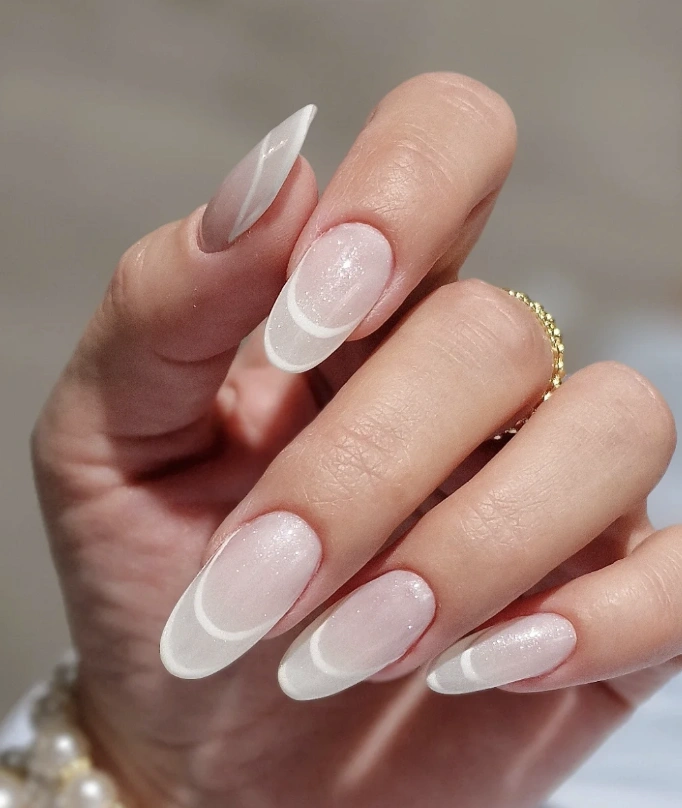 Oval Milky Nude Nails with Glossy White French Tips and Subtle Glitter