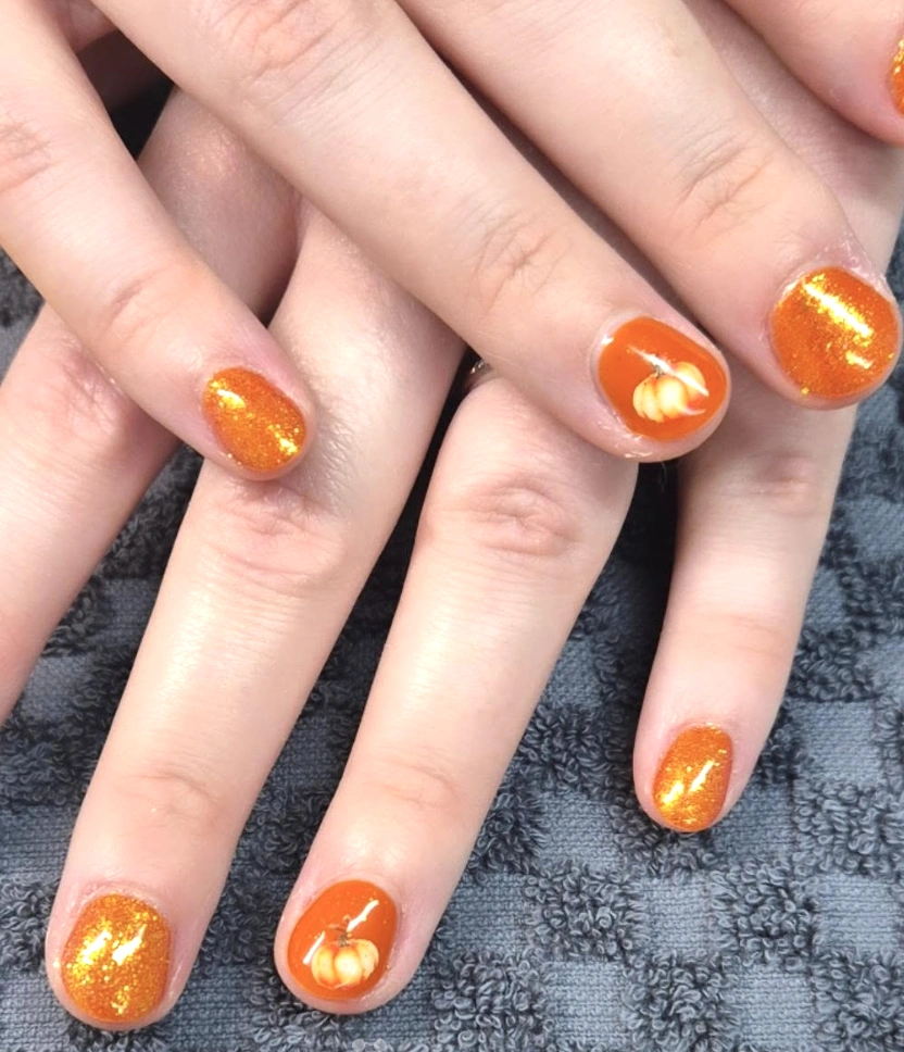 Short Autumn Nails with Pumpkin Accents and Shimmering Orange Tones