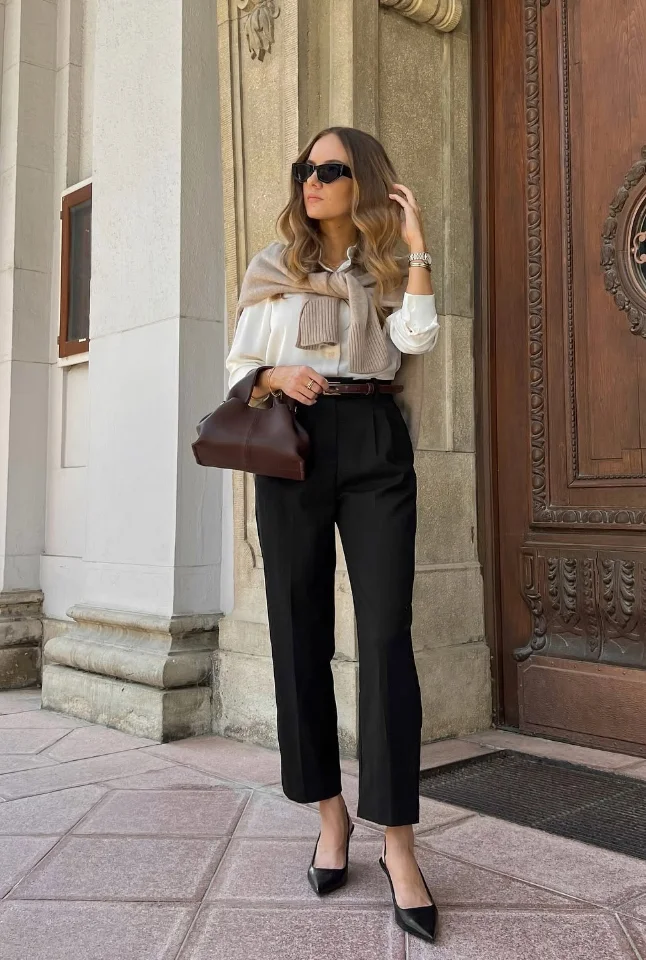 White Button-Up Shirt + Light Beige Sweater Draped Over Shoulders + Black High-Waisted Straight-Leg Trousers + Black Pointed-Toe Heels